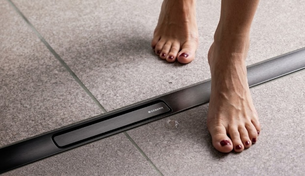 รางระบายน้ำ Geberit ทรงยาวติดตั้งในพื้นกระเบื้องบริเวณเท้าผู้ใช้